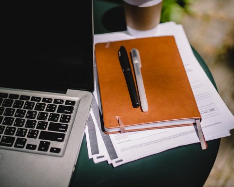 planner and pens on table with laptop