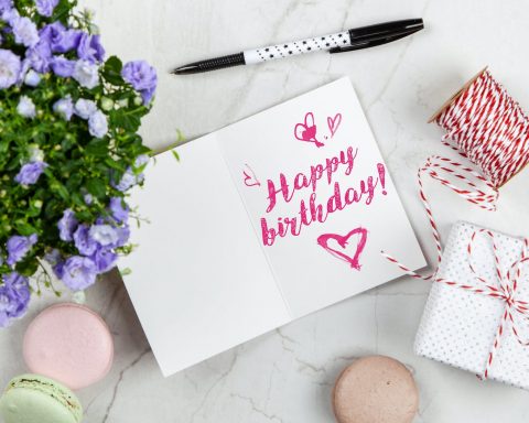 happy birthday card beside flower thread box and macaroons