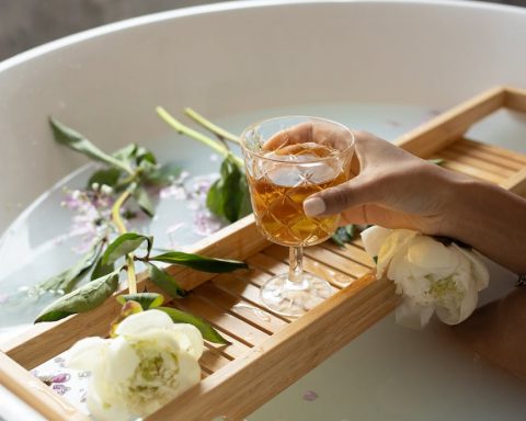 woman with wineglass and flowers in bathtub