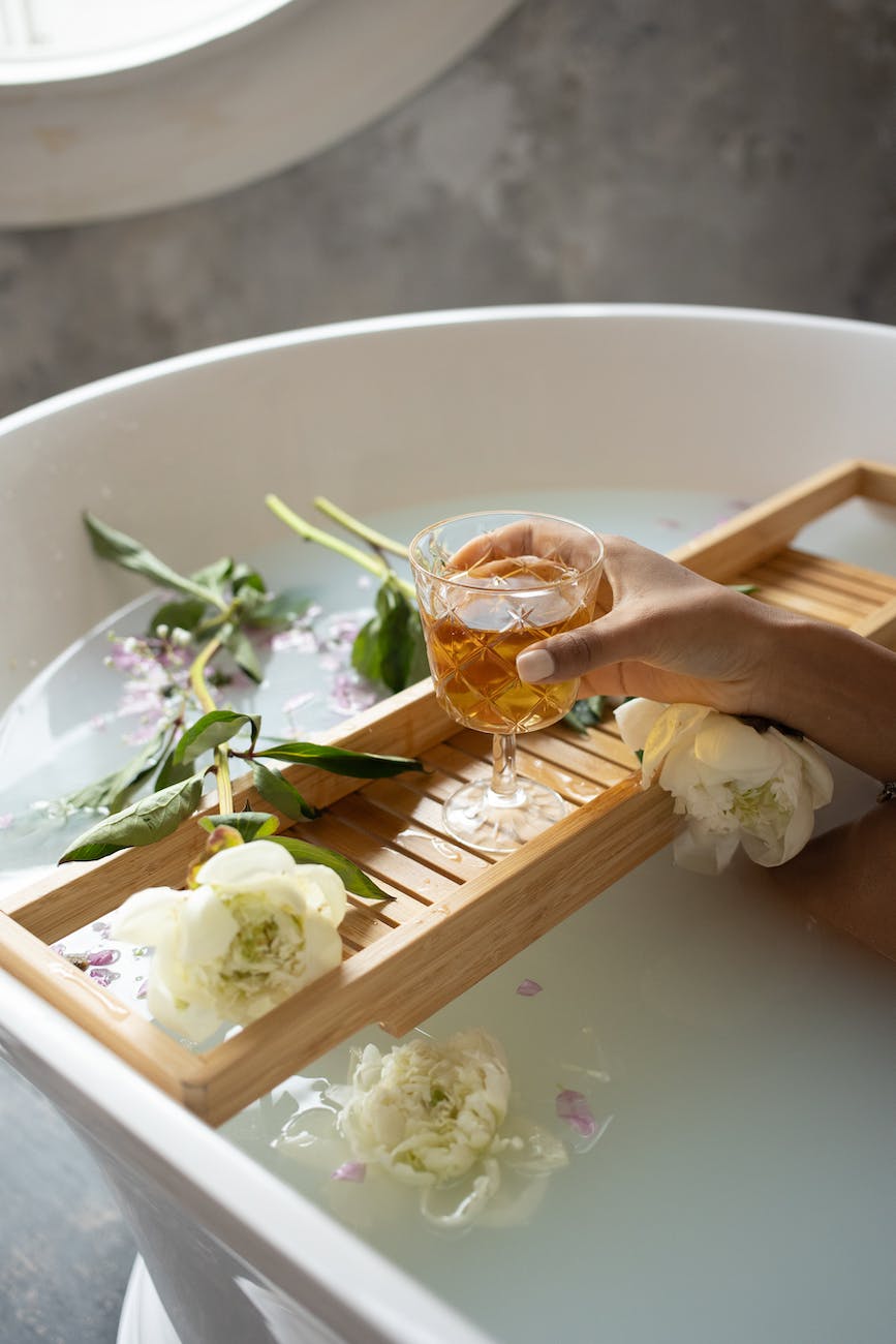 woman with wineglass and flowers in bathtub