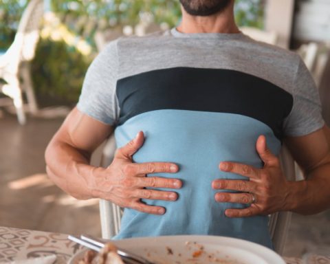 man with hands on his abdomen suffering after eating too much