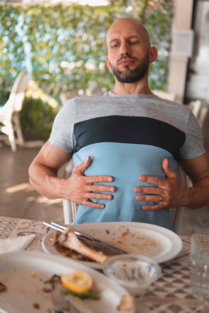 man with hands on his abdomen suffering after eating too much