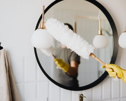 crop woman dusting lamp during housework