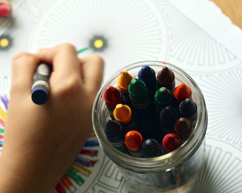 person coloring art with crayons