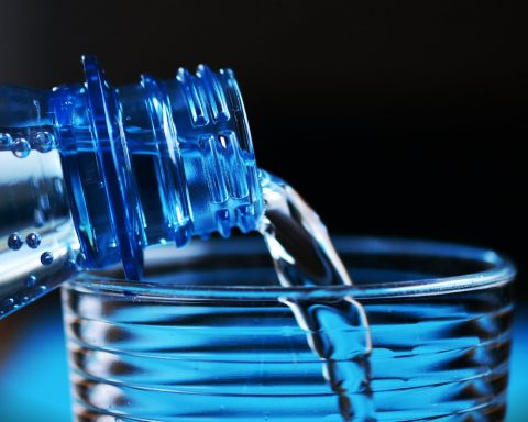 close up of bottle pouring water on glass