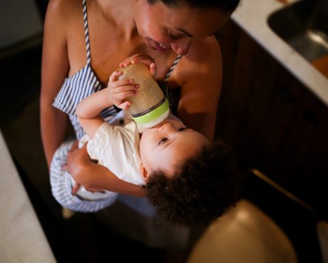 a mother bottle feeding the baby she is carrying