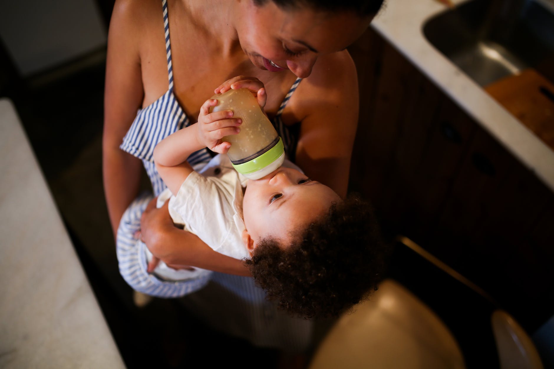 a mother bottle feeding the baby she is carrying