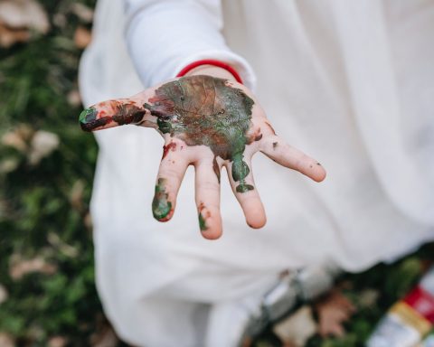 girl sitting on grass and showing dirty hand